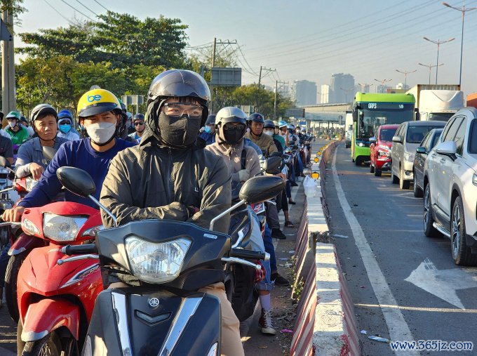 Người dân mặc áo ấm， khoanh tay giữ ấm khi dừng xe máy ở ngã tư Võ Nguyễn Giáp - Tây Hoà， TP Thủ Đức. Ảnh: Đình Văn